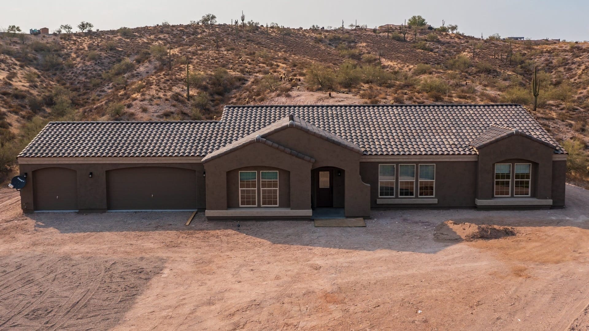 Brown Stucco house in a dirt lot