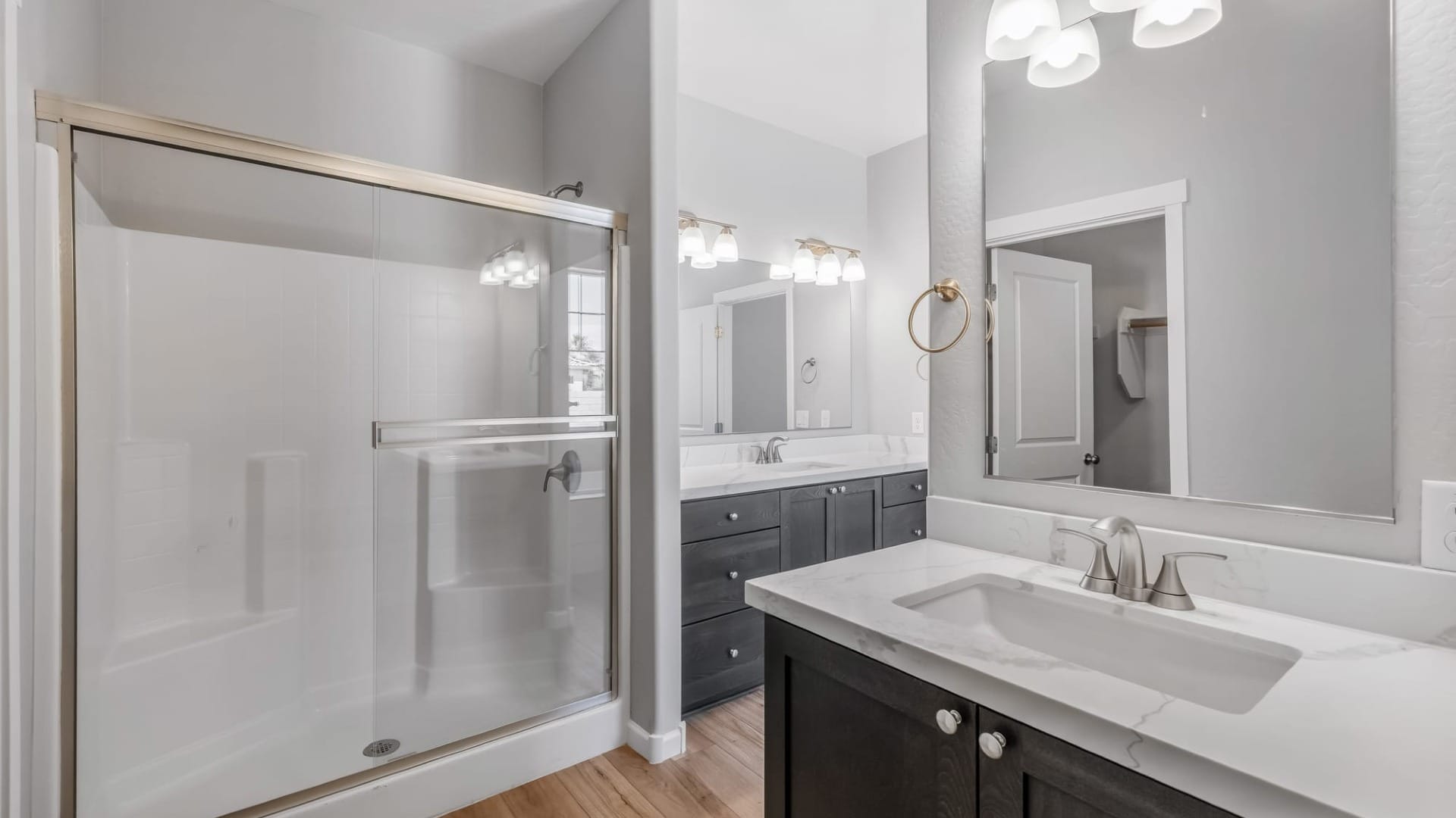 Custom home bathroom with double sink vanity, quartz countertops, modern fixtures, and glass enclosed shower.