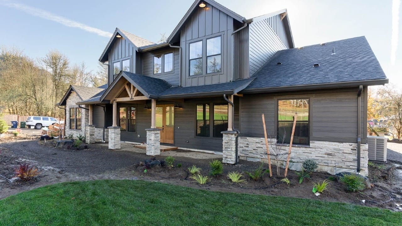 A dark pain house in front of a gravel driveway