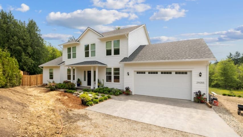 A two-story white house with a concrete driveway