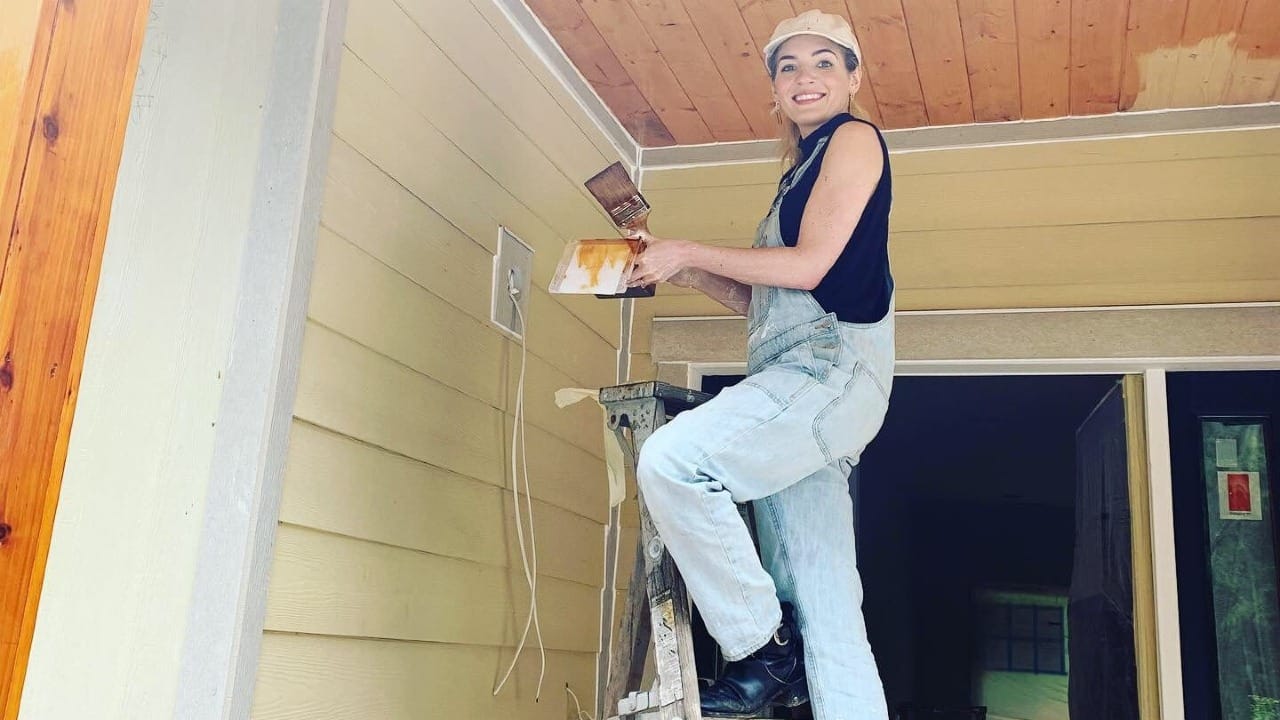 A lady painting a house