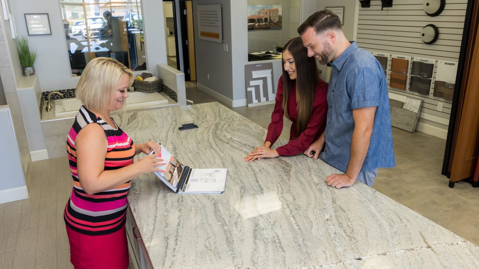 A lady showing something on a laptop to a couple