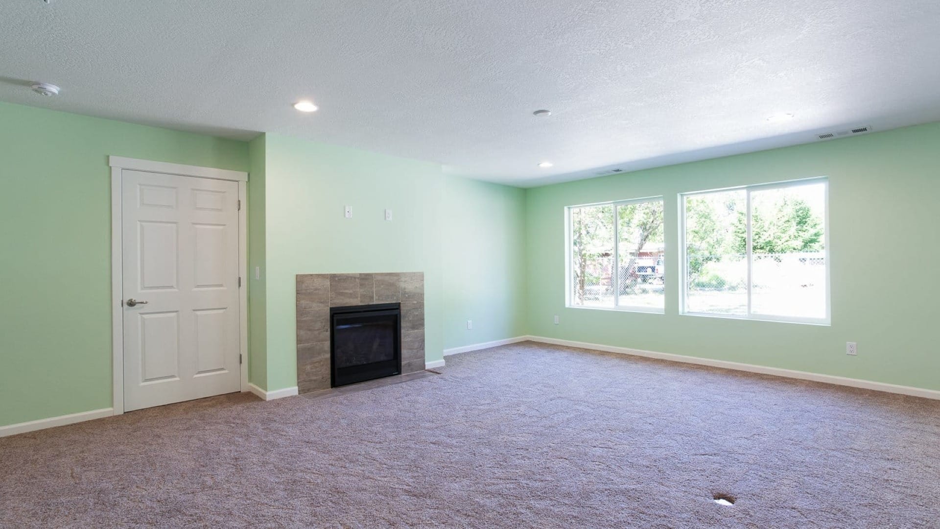 Living Room Oswego with green walls, a grey tile fireplace and a grey carpet flooring