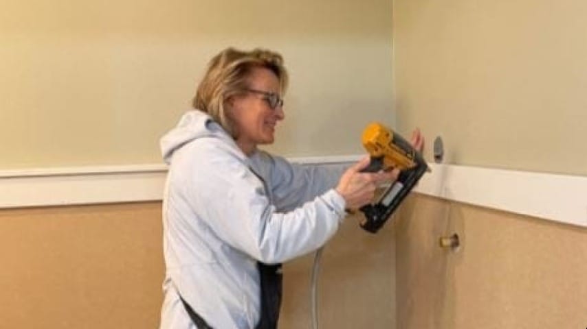 Lady using a nail gun on a wall