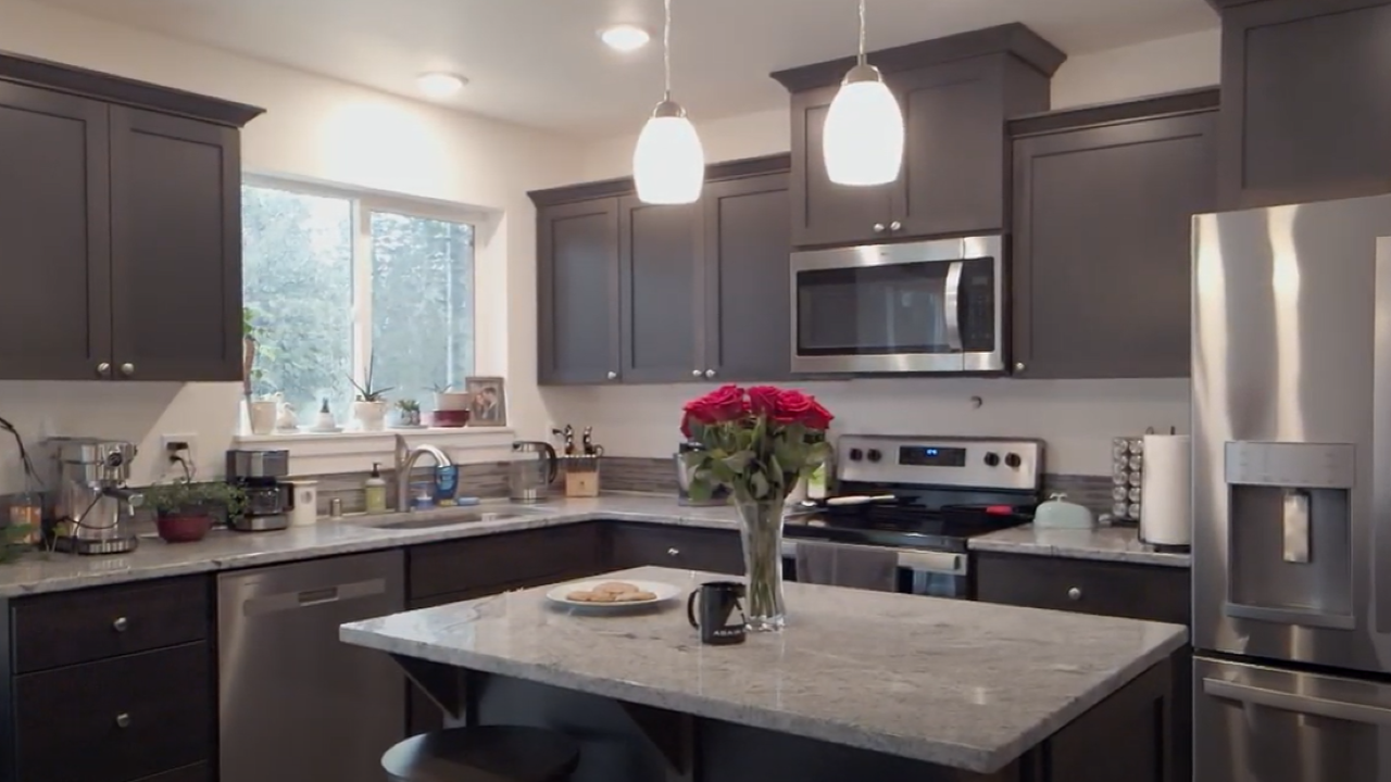 A kitchen with a vase of roses on the island countertop