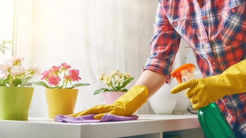 Person cleaning a table with some flowers on it