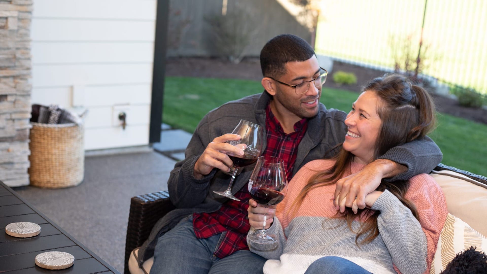 A couple drinking wine on their outside couch