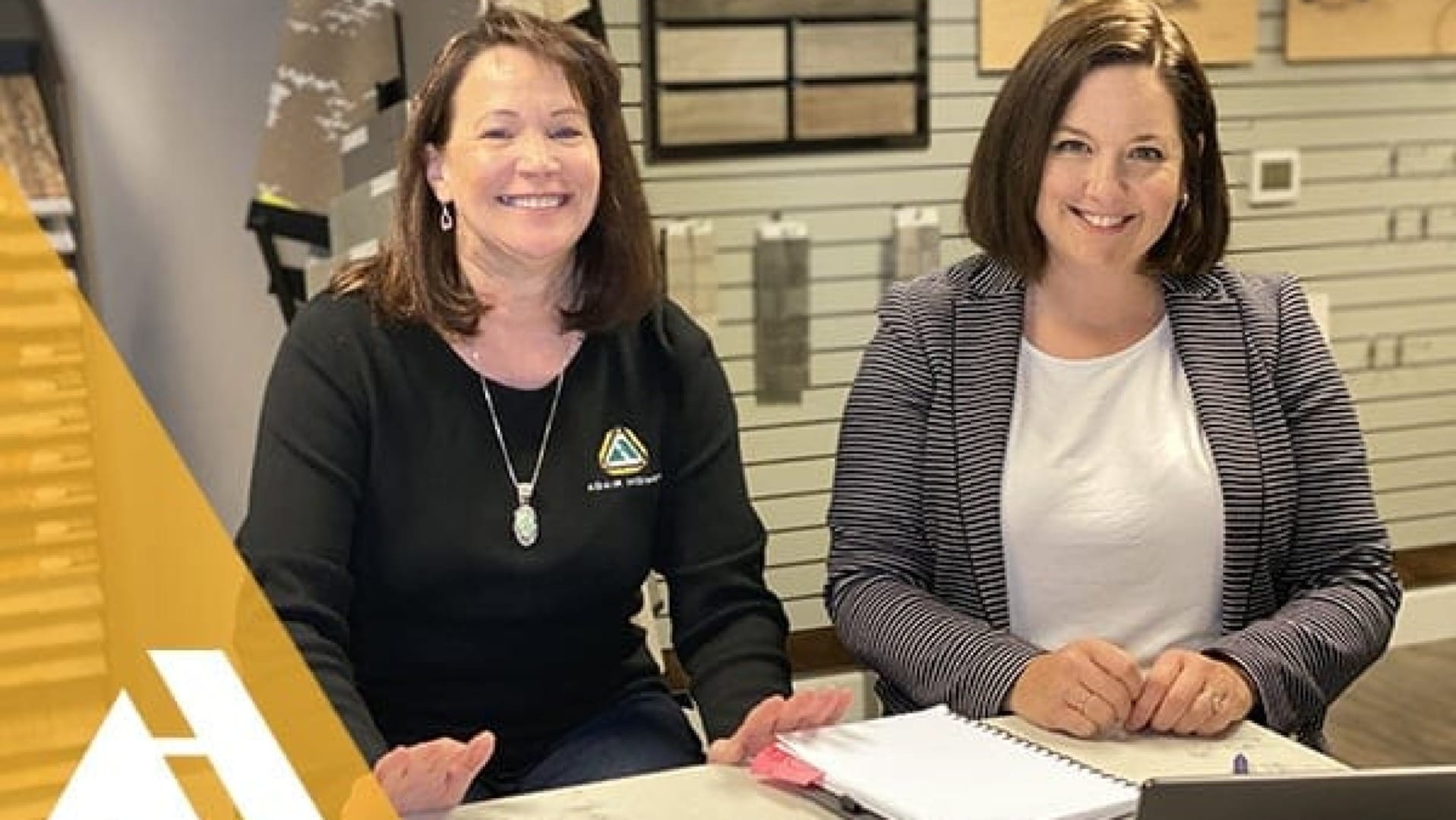 two Adair home women smiling towards camera in the Adair homes office