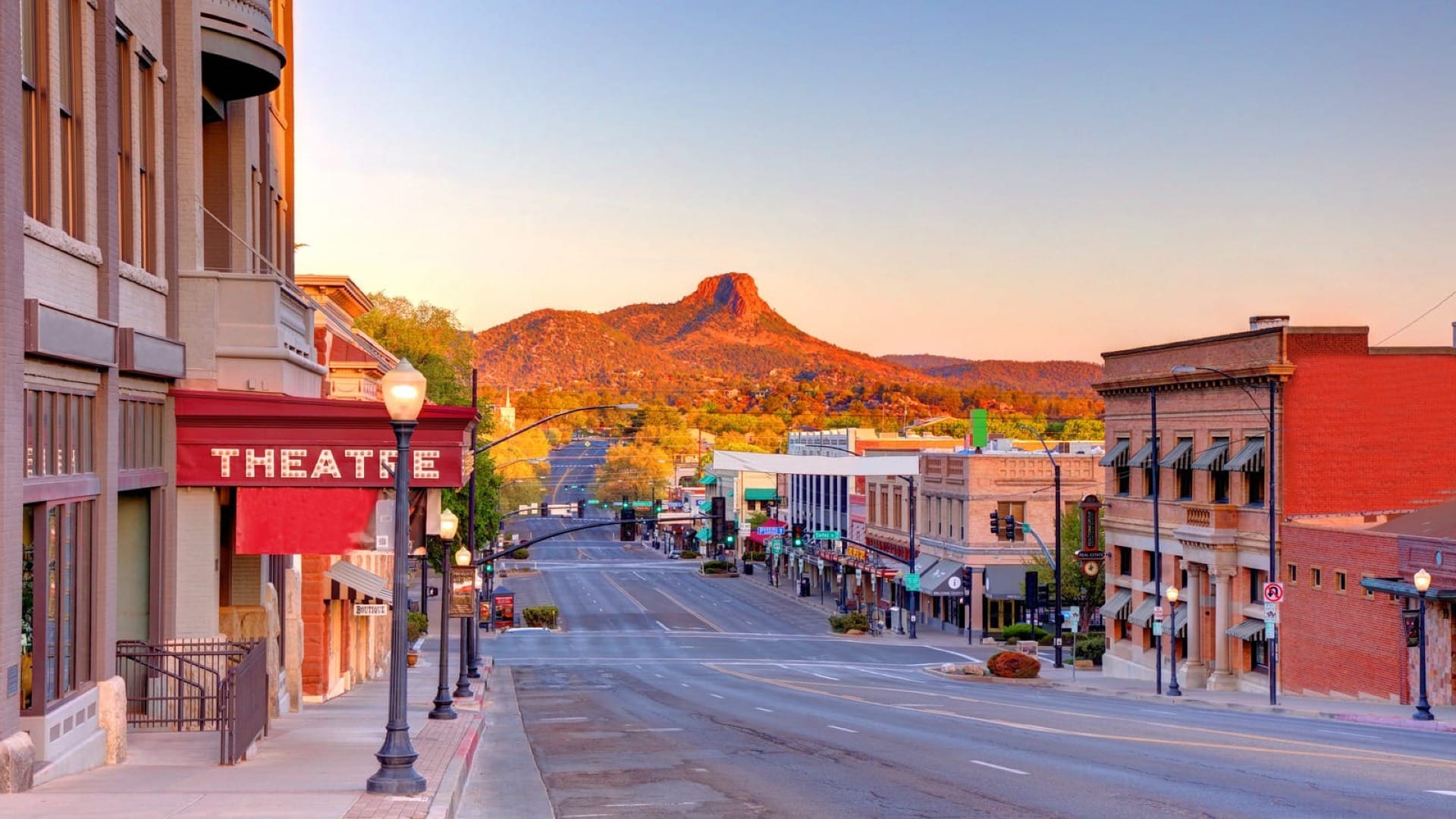A street view of a small town in Arizona with a massive rock formation in the backround