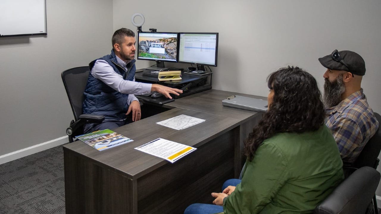Man helping a couple talk about a new house