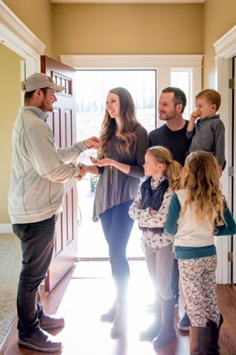 family of four getting their keys for their new home from a Adair homes rep in their new home