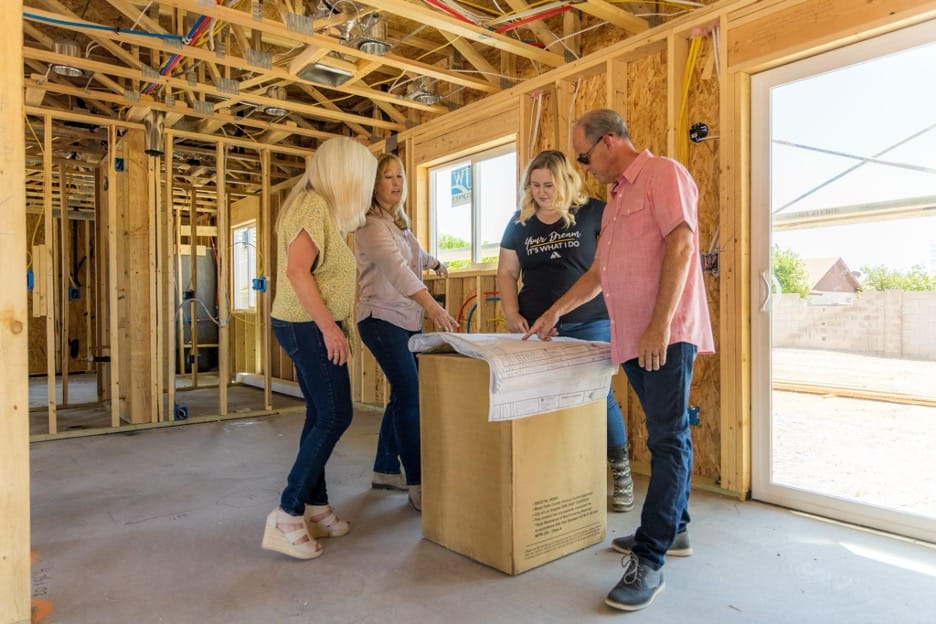 three women and one man inside a under contruction home by Adair homes looking over blue prints