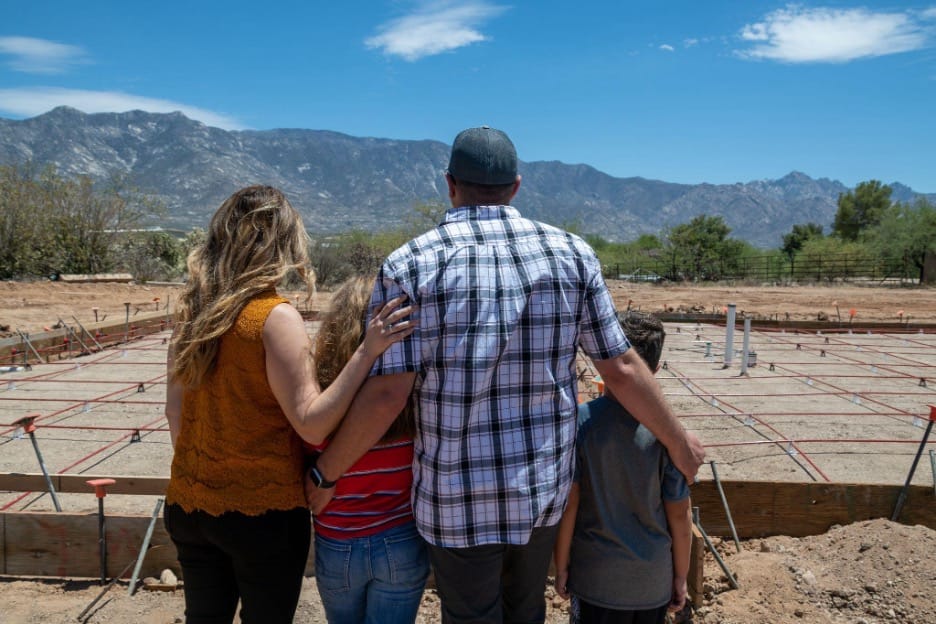 family of 4 standing in front of their newly poured founation