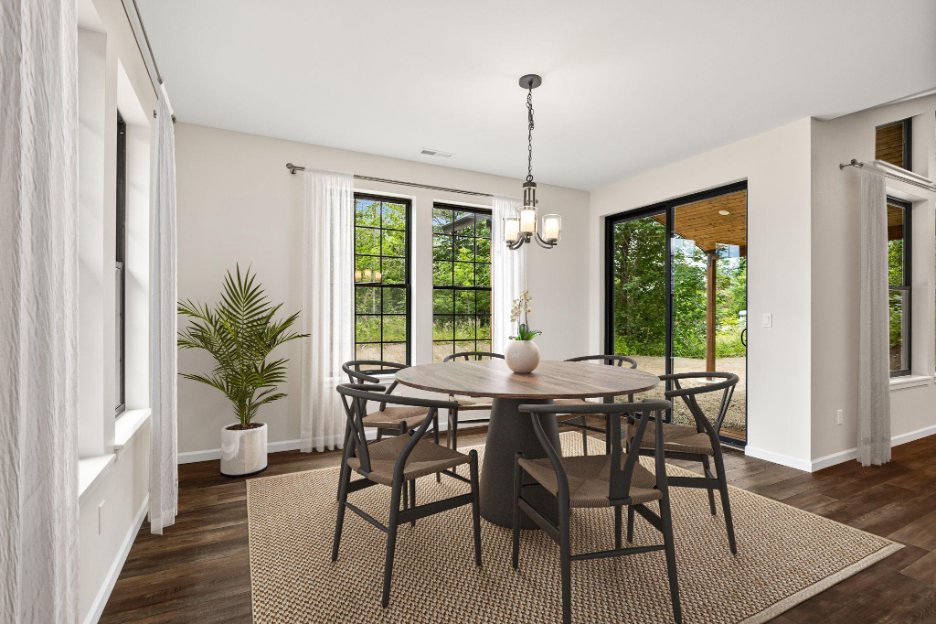 Bright dining room with large windows, sliding glass doors, neutral tones, and natural light highlighting a round table and modern décor.