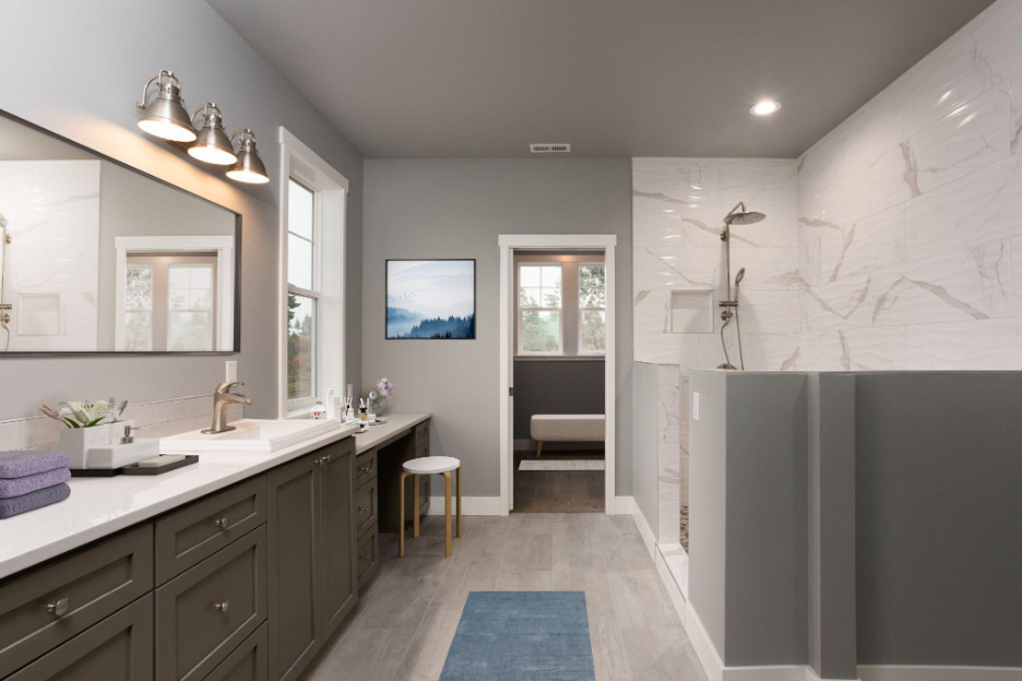 Elegant bathroom featuring dual vanities, a large walk-in shower with marble tile, and soft gray walls for a spa-like atmosphere.