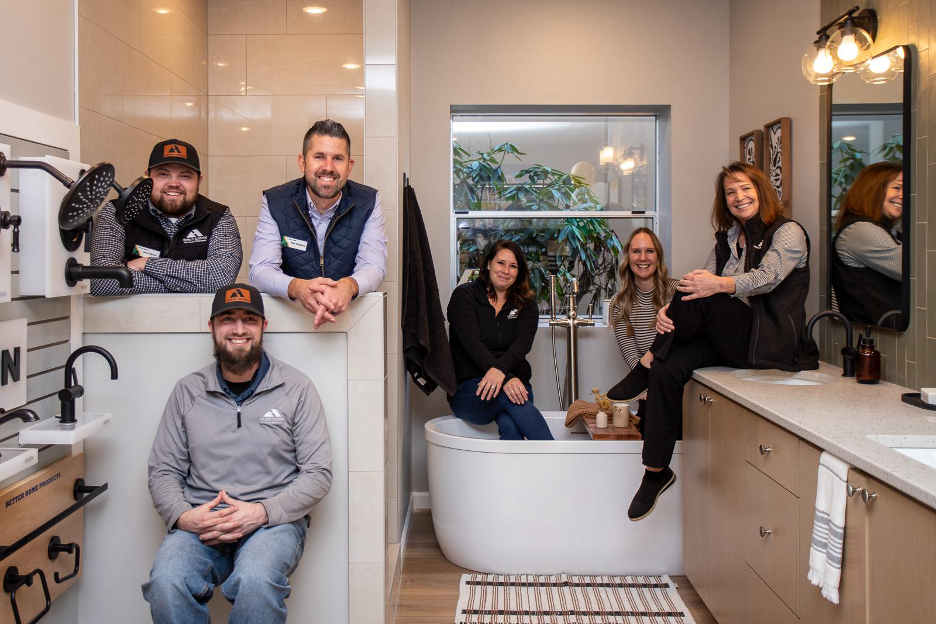 Friendly Adair Homes team posing together in a stylish bathroom showroom, showcasing design expertise and collaboration.