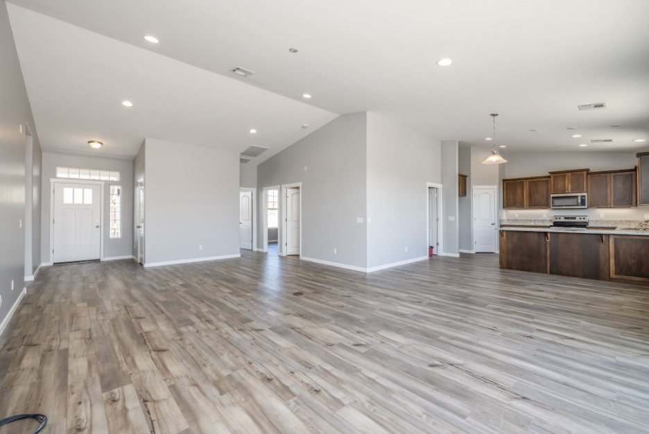 Spacious open-concept interior featuring wood-look flooring, vaulted ceilings, and a bright kitchen with modern cabinetry and stainless steel appliances.