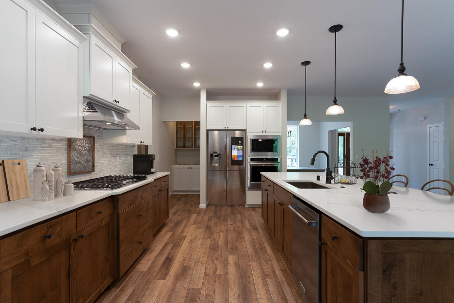 Contemporary kitchen design featuring a large island, white and wood cabinetry, stainless steel appliances, and pendant lighting.