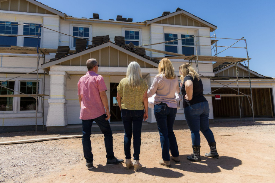 Clients visiting an Adair custom home under construction, viewing progress on a two-story home with scaffolding and exterior framing.
