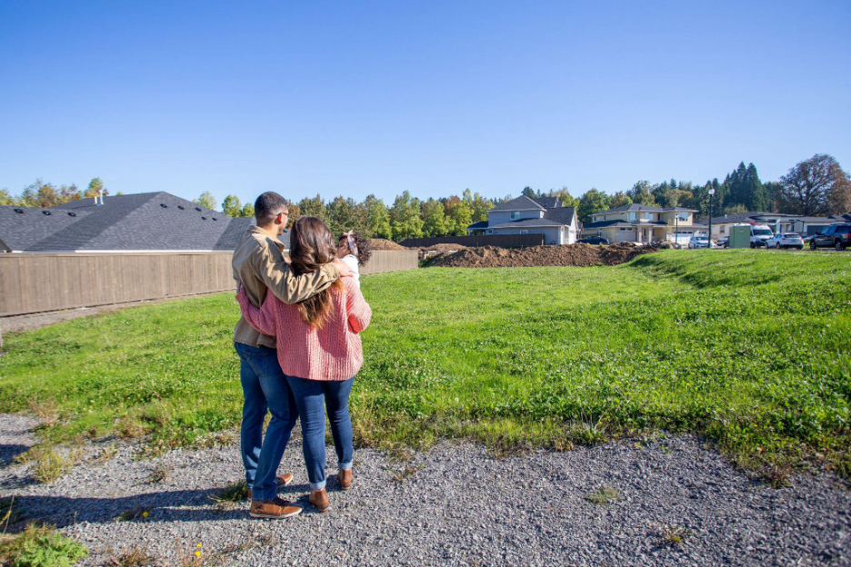 Family standing on their property looking out over an open lot where their future custom home will be built.