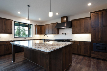 Custom home kitchen with dark wood cabinets, large island, stone countertops, and modern lighting.