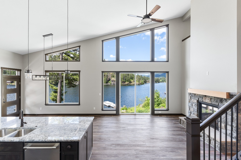 Open-concept living room with large windows, vaulted ceiling, and lake view showcasing Pacific Northwest scenery.