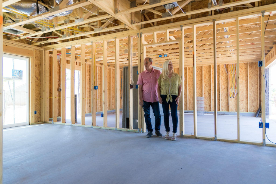 Homeowners walking through a custom home during framing stage, viewing layout and structure before drywall.