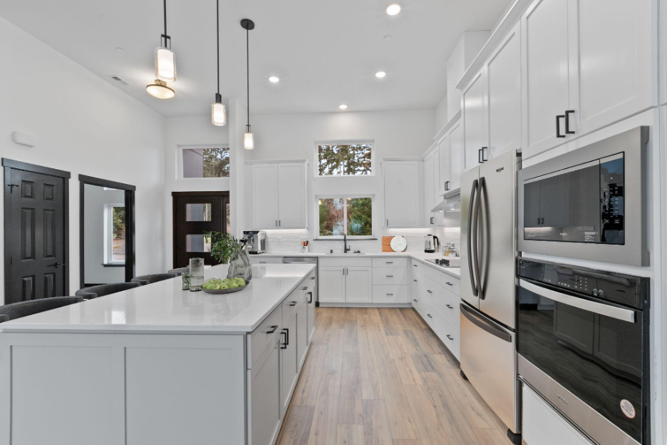 Bright modern kitchen in a custom Phoenix home featuring large island, white cabinetry, and stainless steel appliances