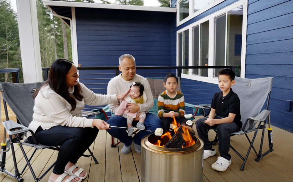 Family enjoying an outdoor living area at their custom-built home with deck seating and fire pit