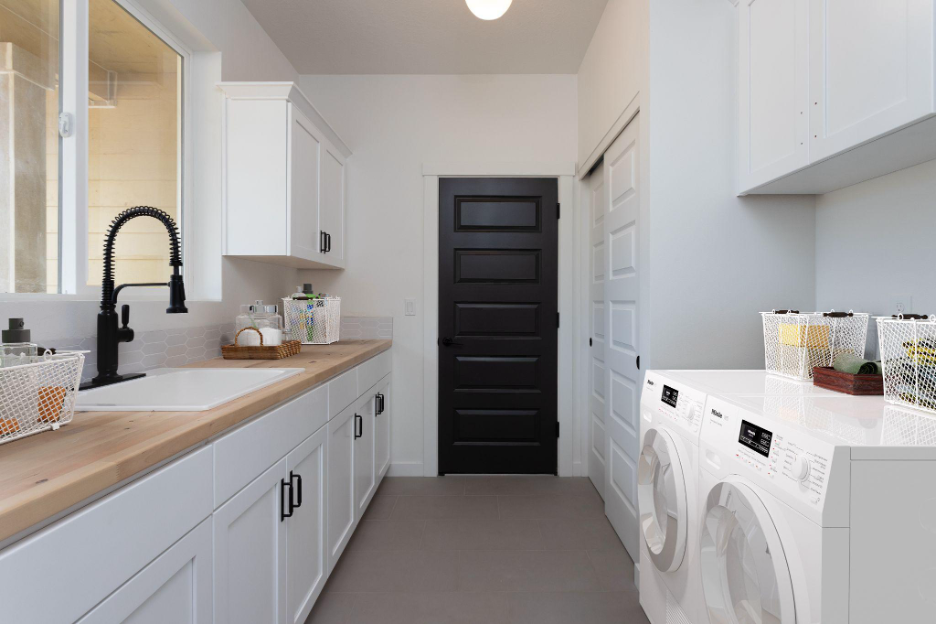 Custom laundry room with white cabinetry, wood countertops, and modern washer and dryer