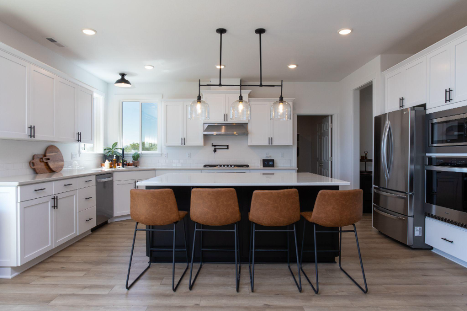 Custom kitchen with large island, white cabinetry, pendant lighting, and stainless steel appliances