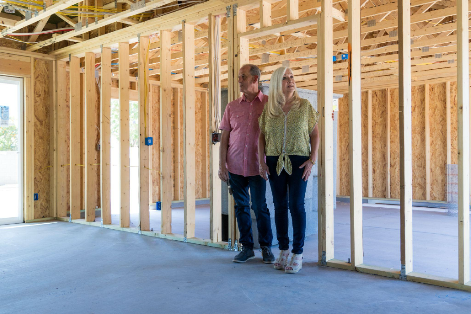 Homeowners walking through the framed interior of their custom home during construction