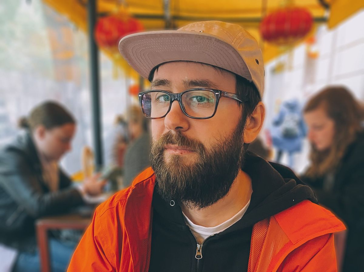 Otro chico más con barba, gafas y corra, mirando a cámara más o menos serio.