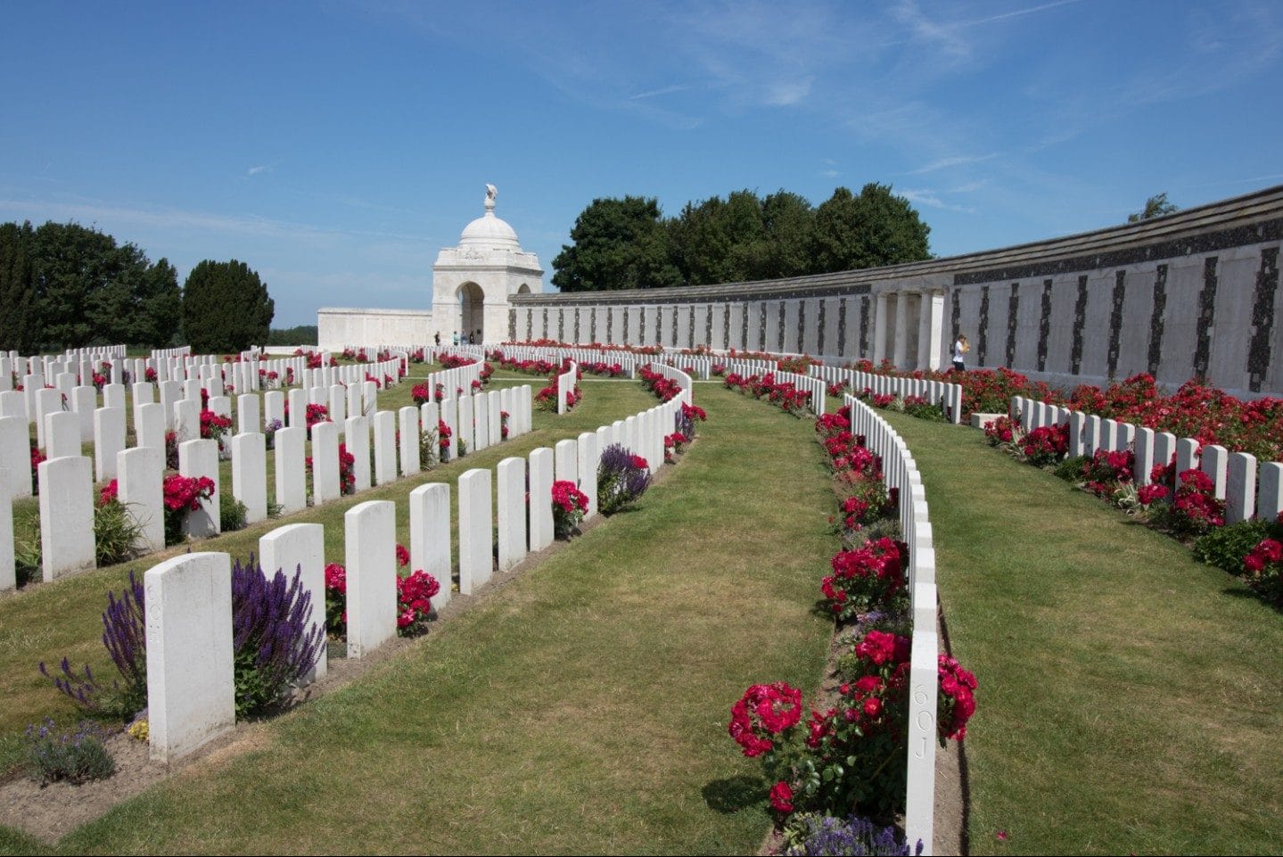 Rows of white marble crosses marking graves at the Flanders Field American Cemetery in Belgium, set against a manicured green lawn under an overcast sky, memorializing soldiers killed in World War I.