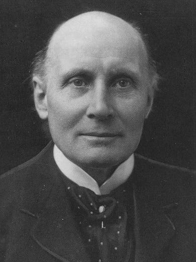 A black-and-white photographic portrait of an elderly, balding man in a dark suit and tie: the philosopher Alfred North Whitehead.