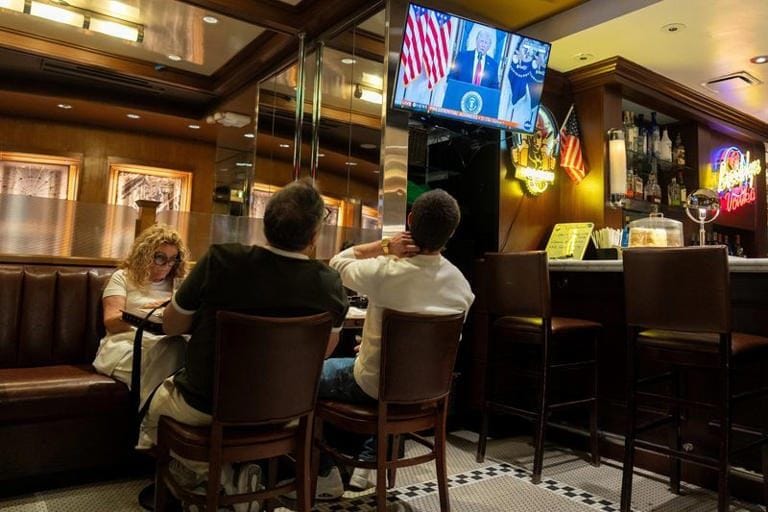 Diners at the Brooklyn Diner in Times Square watching the president’s April 1, 2026 address on a mounted television.