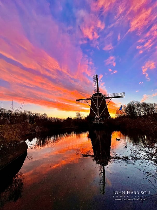 Amsterdam windmill, De Riekermolen, at sunset with warm sky over Amsterdam, The Netherlands.