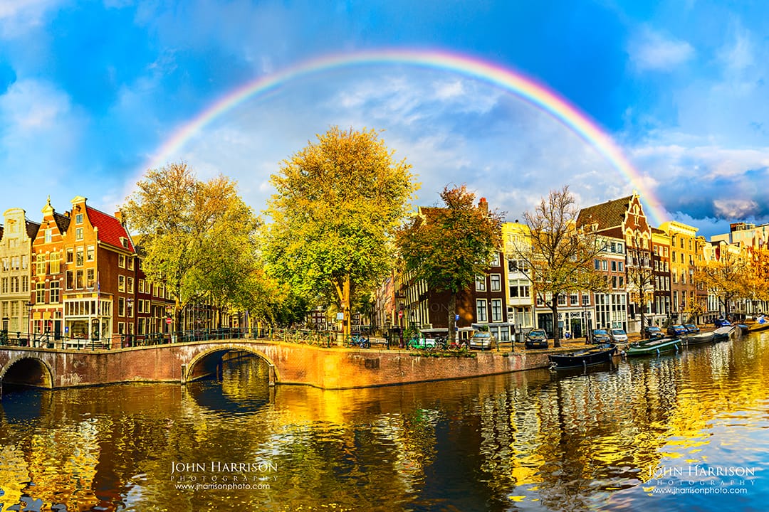 Rainbow over Amsterdam canals with autumn trees and reflections, Amsterdam, The Netherlands.
