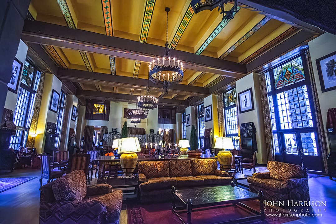 Interior of The Ahwahnee Hotel Great Lounge in Yosemite Valley with timber beams, chandeliers, warm lamps, seating areas, and a cozy winter lodge atmosphere near the fireplace in Yosemite National Park