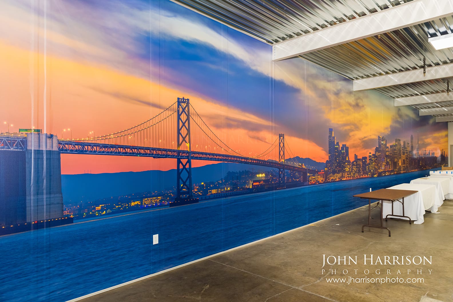 Custom large-scale corporate mural of the San Francisco skyline at sunset, featuring gigapixel photography of the Bay Bridge for a Silicon Valley office installation.