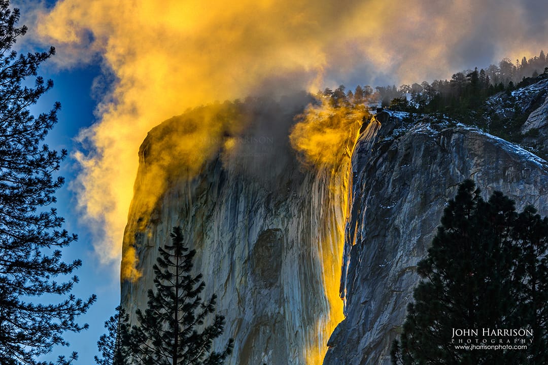 Horsetail Falls glowing orange during the Yosemite Firefall at sunset on El Capitan, with golden clouds and winter trees in Yosemite Valley, Yosemite National Park