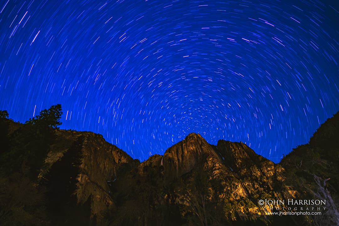 Star trails long exposure swirling above Upper Yosemite Falls and Lost Arrow Spire on a clear winter night in Yosemite Valley, Yosemite National Park