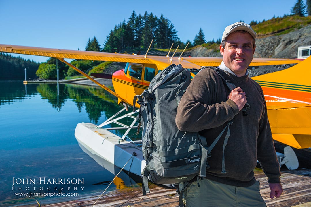 John Harrison nature and landscape photographer standing beside an Alaskan seaplane with his F-Stop Tilopa backpack and Nikon camera gear before departing for Katmai National Park and Preserve Alaska for wildlife photography with f-stop Tilopa camera pack.