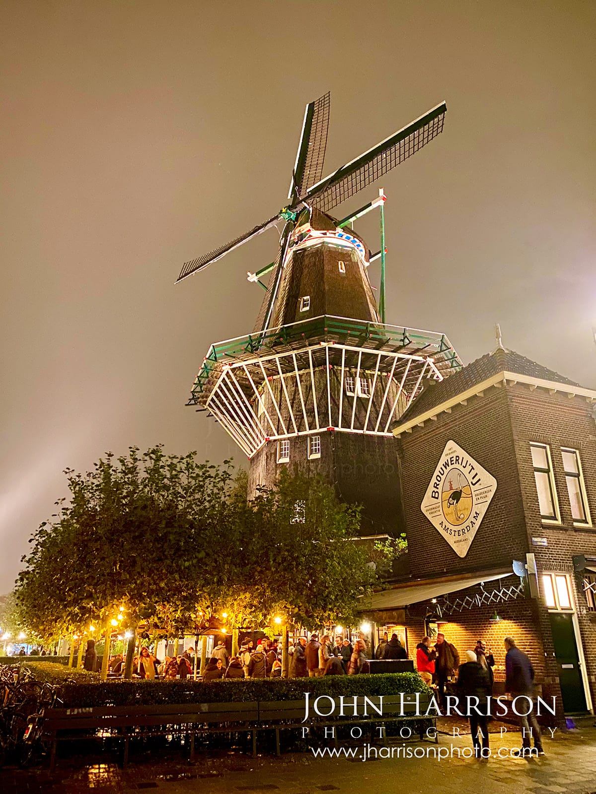De Gooyer windmill in fog at Brouwerij t IJ Amsterdam with crowd gathered below in soft misty light