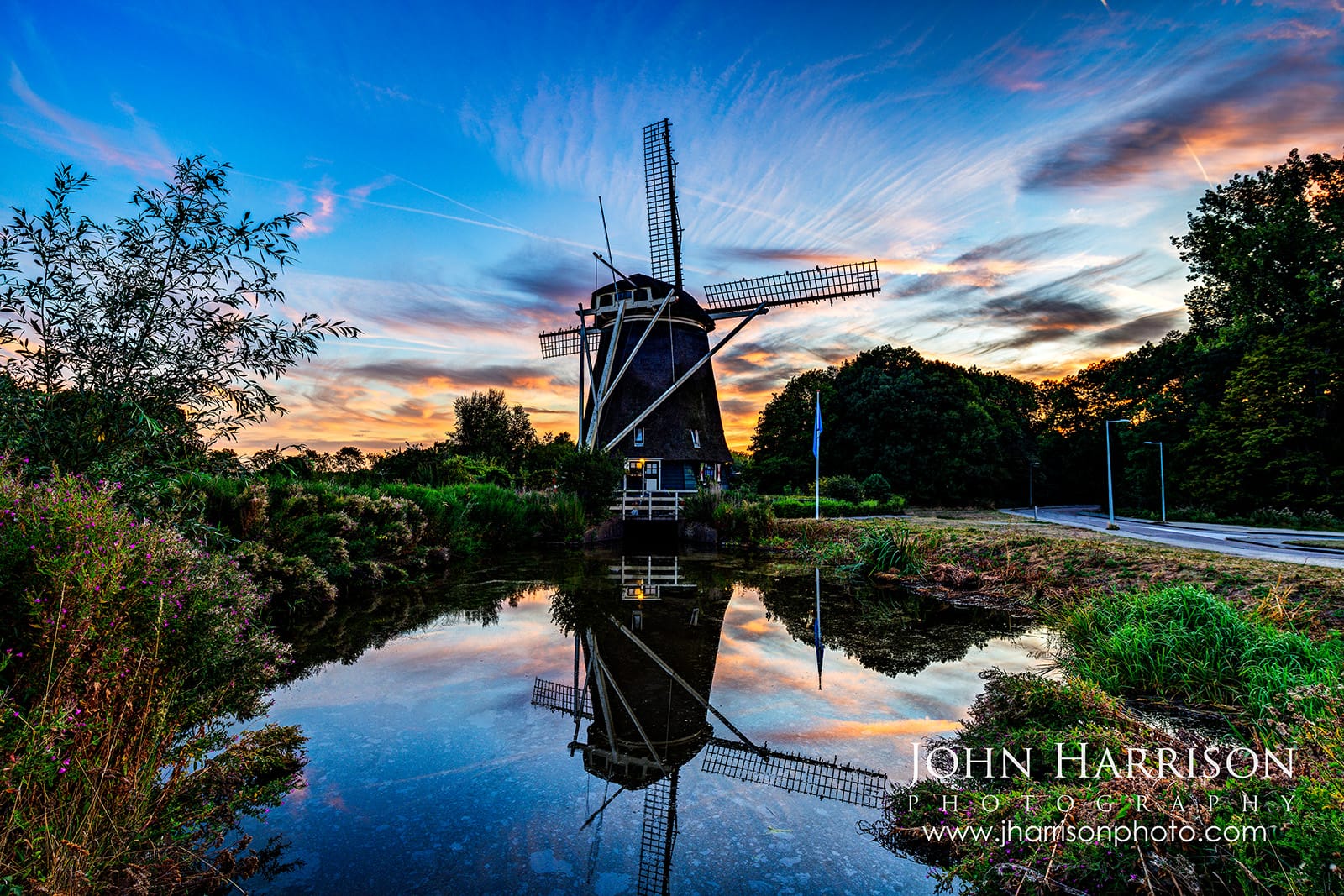 De Riekermolen windmill at sunset along the Amstel River in Amsterdam, Netherlands with reflections in calm water and golden summer light