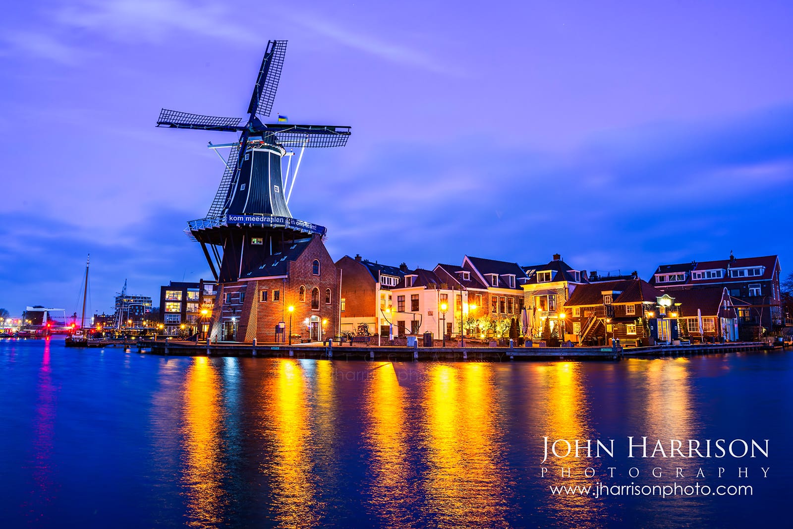 De Adriaan windmill at blue hour in Haarlem Netherlands with city lights reflecting in the Spaarne River near Amsterdam