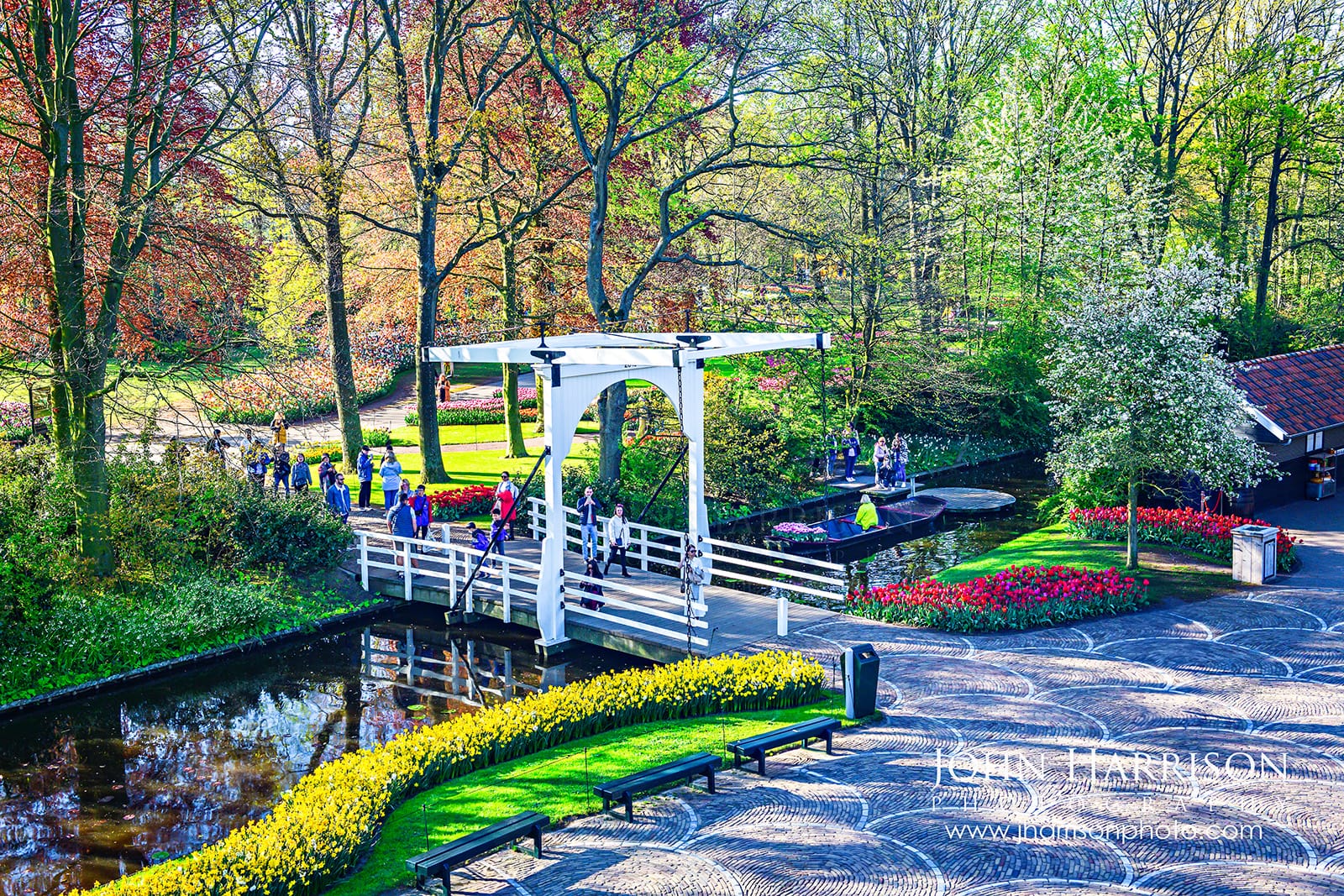 View from windmill at Keukenhof Gardens showing bridge, canal, tulips and visitors in Lisse Netherlands during spring.