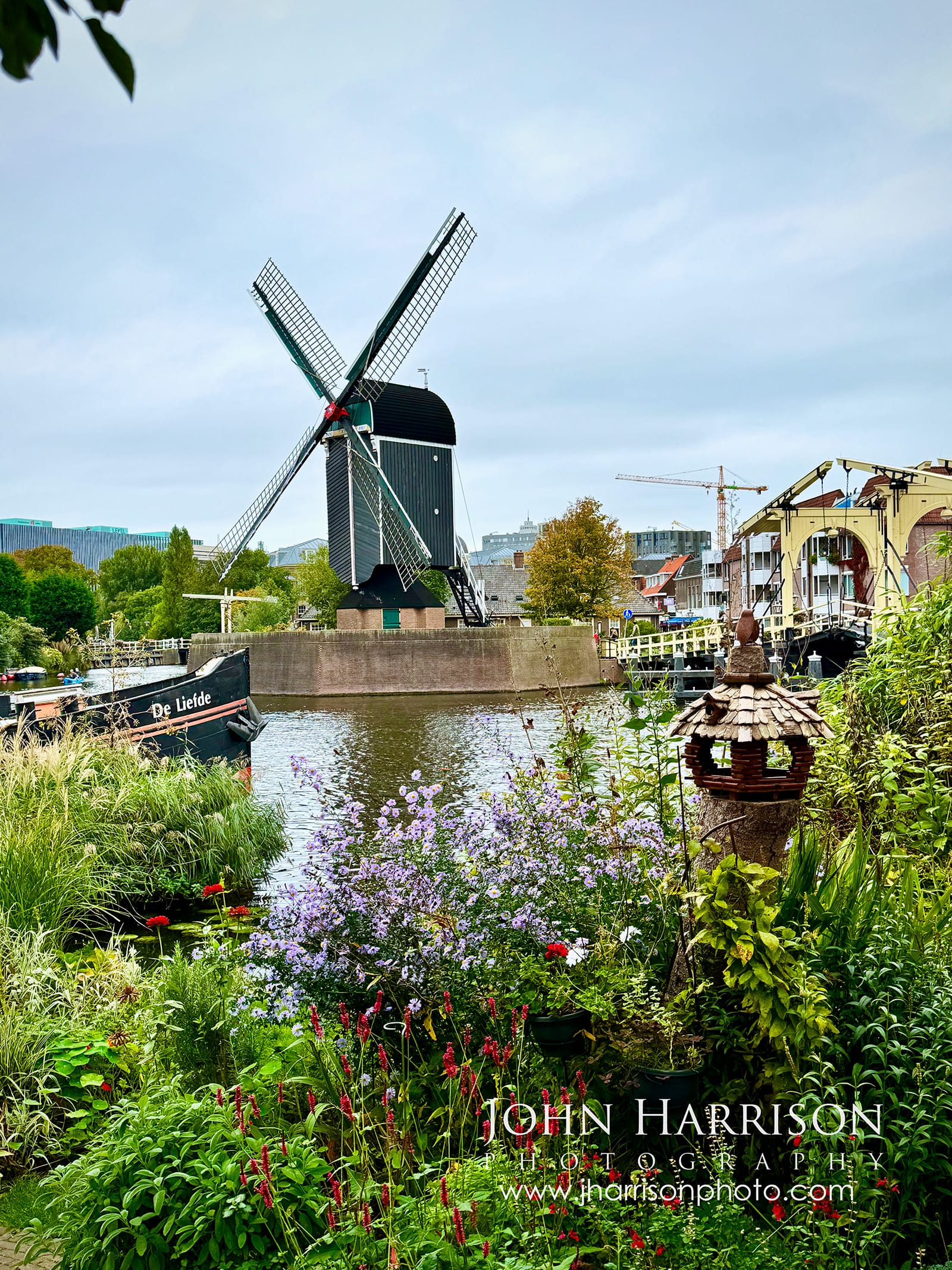 Molen De Put windmill beside canals and colorful summer gardens near Rembrandtbrug bridge in Leiden, Netherlands.