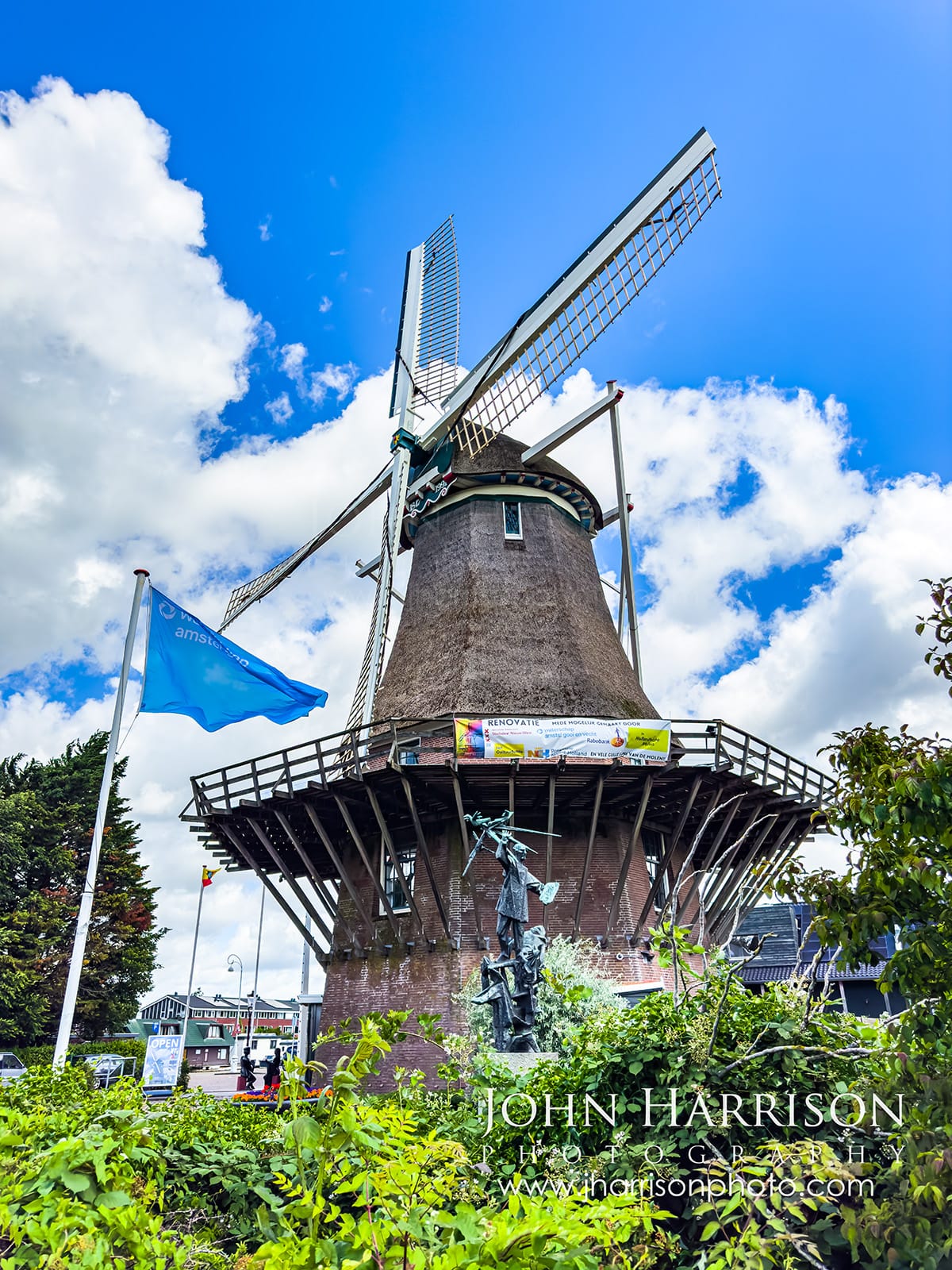 Molen van Sloten windmill in Amsterdam Netherlands with rotating sails and blue sky, a working Dutch windmill open for tours near the city