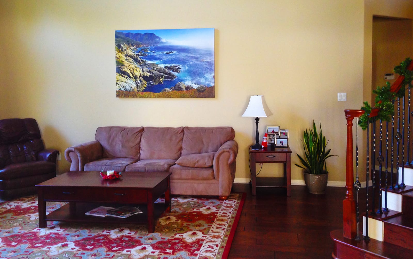 Large canvas print of the Big Sur coastline displayed above a sofa in a living room, featuring rugged cliffs, coastal fog, and Pacific Ocean views along California's Highway 1.